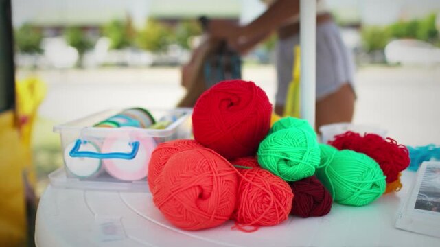 Many threads and ribbons lie on the table against the background of a girl whose African braids are weaving