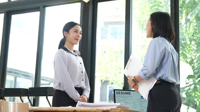 HR manager interviewing a job candidate across a desk, discussing qualifications and experience during a recruitment meeting in a modern office environment.