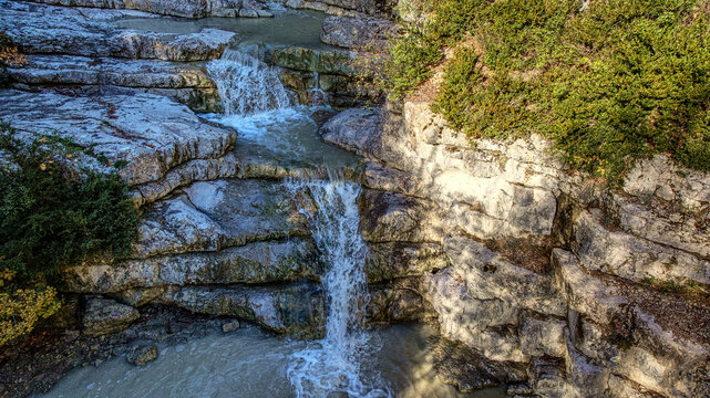 A stunning capture of Aulan's wild beauty, featuring a tiered waterfall over rocky cliffs
 and a winding river through a lush green valley
. This landscape highlights rugged mountains,.