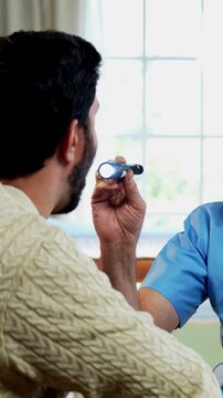Indian male doctor checking male patient with torch during routine medical examination as experienced physician assesses young man inside modern Indian clinic OPD healthcare visit