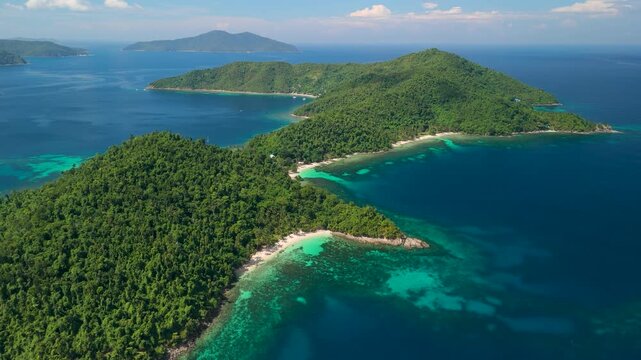 Drone rises over lush jungle-covered Maxima Island revealing white sand beaches turquoise reef waters and deep blue ocean in Palawan Philippines