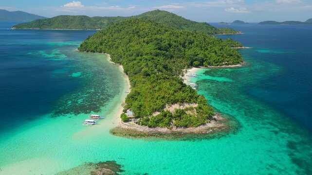 Aerial view of lush Maxima Island in Philippines with white sandy beaches, turquoise coral waters and bangka boats moored along shoreline - approaching in parallax