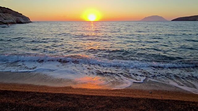 Experience the stunning sunset as it casts golden hues over the serene waters of Milos. The gentle waves lap at the pristine beach, creating a peaceful holiday atmosphere.