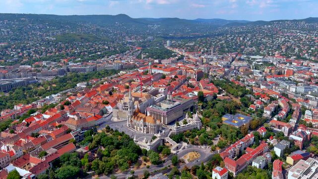 4K aerial drone footage over Budapest, Hungary. Matthias Church, Fisherman's Bastion, Holy Trinity Column, and Castle District on Buda hill with Buda Hills backdrop, summer.