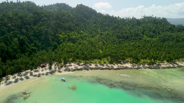 Rising pullback aerial over Coconut Beach Port Barton Palawan revealing long curved bay with white sand, coconut palms and turquoise water