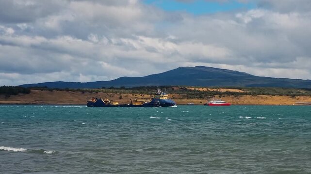 A working dredger navigaA dredging vessel moves through the waters of &Uacute;ltima Esperanza Fjord near Puerto Natales, Chile, framed by the rugged Patagonian landscape in an everyday maritime working scene
