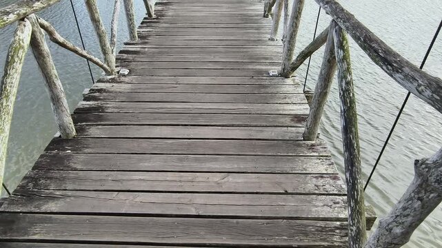 A wooden boardwalk bridge curving across a lake