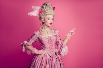 Fototapeta premium Photo of lady queen princess pointing finger empty space wearing antique baroque style dress isolated pink color background