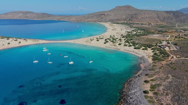 Simos Beach in Elafonisos offers stunning views of turquoise waters and sandy shores. Sailboats drift peacefully while the sun shines over the idyllic landscape. Elafonisos Island Greece