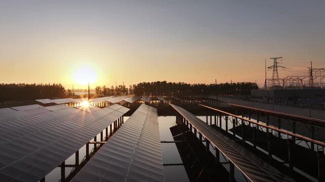 Solar photovoltaic power station array on water at sunset with reflections and industrial infrastructure