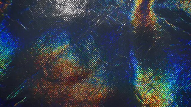 Macro shot of shiny holographic metallic fabric texture with vibrant rainbow glitter reflection.