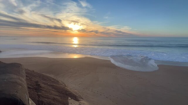 Static 4K shot of a peaceful sunset at Labenne Oc&eacute;an, France, featuring a natural tidal pool (ba&iuml;ne) and gentle waves on the Atlantic coast.