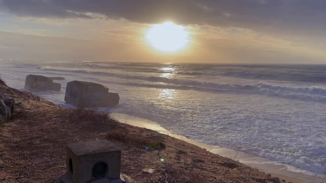 4K static shot, Feb 17 2026, Labenne Oc&eacute;an. Waves crash against historic WWII Atlantic Wall bunkers, remnants of the Luftwaffe radar station.