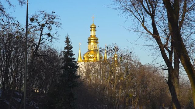 An Orthodox Bell tower with golden domes surrounded by a flock of crows