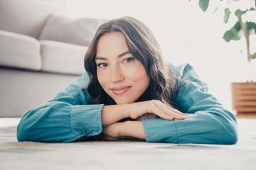 Naklejka premium Relaxed young woman portrait lying on living room floor smiling, cozy home lifestyle and natural beauty closeup