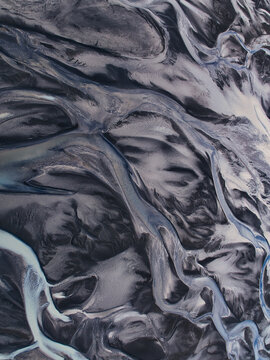 Aerial view of the intricate patterns of a braided glacial river system flowing through volcanic black sand in Kirkjubaejarklaustur, Skaftarhreppur, Iceland.