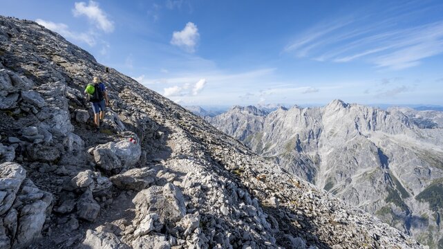 Mountaineer on rocky path to Watzmann Hocheck summit, view of mountain panorama with rocky summit of Hochkalter, Berchtesgaden National Park, Berchtesgaden Alps, Bavaria, Germany