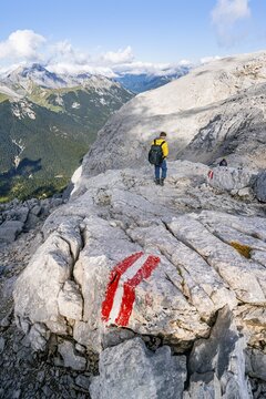 Hikers descending from Hohe Munde, marking on the hiking trail, behind rocky ridge of the Wetterstein mountain range, Mieminger Kette, Tyrol, Austria