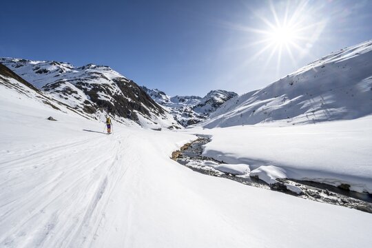 Ski tourer in the snow by a mountain stream in the Funtauna Valley, Sonnenstern, Graub&uuml;nden Haute Route, Albula Alps, Rhaetian Alps, Graub&uuml;nden, Switzerland