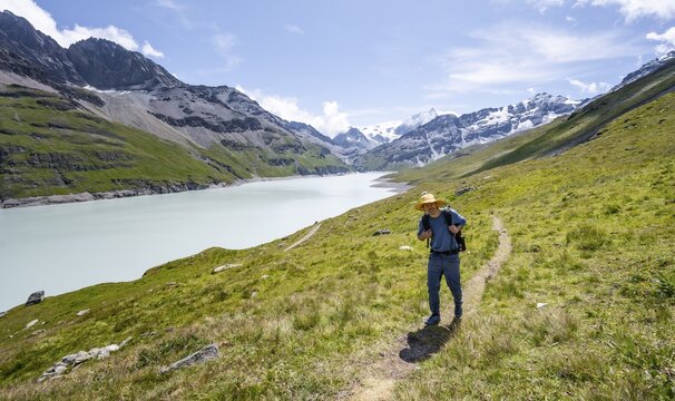 Mountaineer on a hiking trail at a blue mountain lake, Lac des Dix reservoir, Valais Alps, Valais, Switzerland