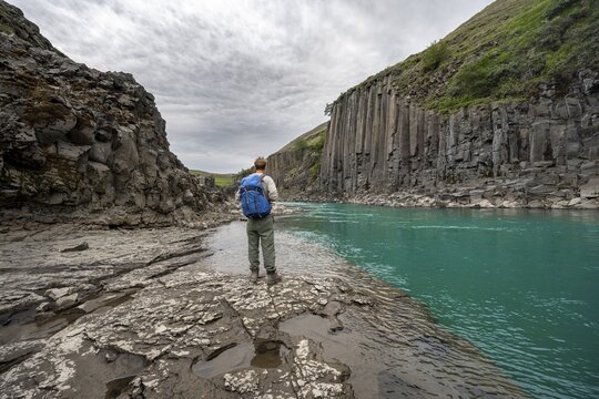 Tourist standing by the river in Stu&eth;lagil Canyon, turquoise blue river between basalt columns, Egilsstadir, Iceland