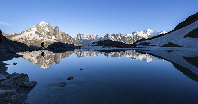 Mountaineer, silhouette in front of mountain landscape in the evening light, water reflection in Lac Blanc, mountain peak, Aiguille Verte, Grandes Jorasses, Aiguille du Moine, Mont Blanc, Mont Blanc massif, Chamonix-Mont-Blanc, Haute-Savoie, France