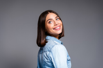 Obraz premium Smiling young woman in denim jacket looking over shoulder portrait conveying happiness confidence and casual style