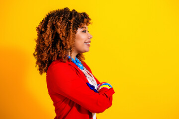 Confident smiling woman in red jacket with curly hair posing in profile against a bright yellow background, colorful accessories and bold fashion portrait conveying joy and style © deagreez