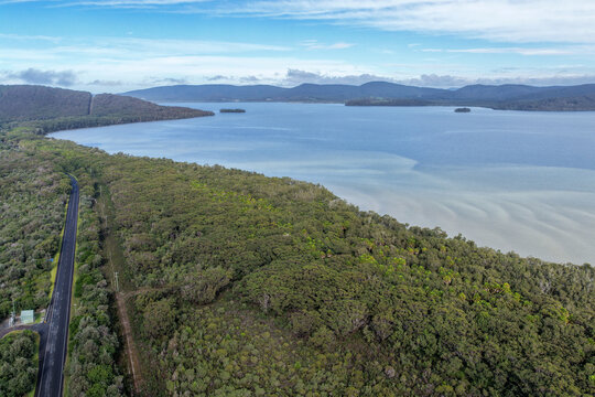 Aerial scene capturing Wallis Lake and Booti Hill near Forster, NSW, Australia. The expansive lake waters, surrounding bushland and prominent coastal hill showcase the diverse landscapes