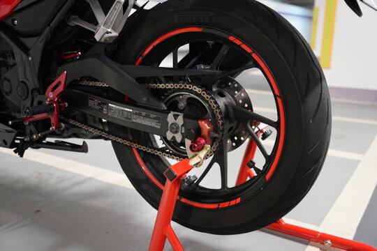 Close up of a motorcycle rear wheel on a red paddock stand.