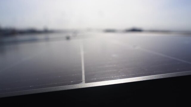 Close-up tracking shot of a modern rooftop solar panel array, revealing the mounting infrastructure and modular design with an urban cityscape in the background