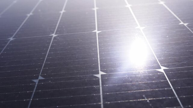 High-detail close-up of a modern photovoltaic solar panel surface, highlighting the crystalline structure, busbars, and reflective sun flare on the module
