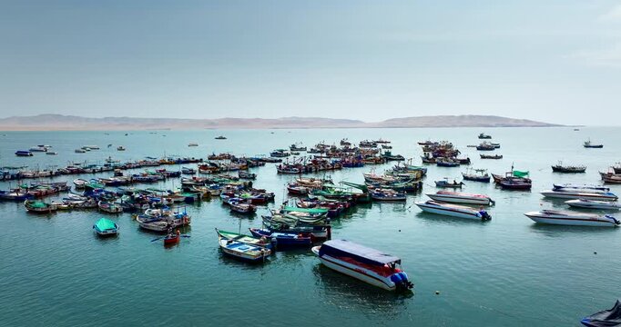 Fishing boats anchored in Paracas Bay along the Peruvian coast, aerial overview at calm morning in rural harbor