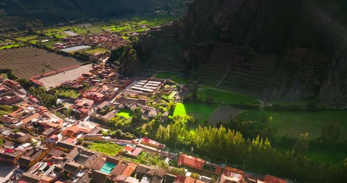 Drone view of historic settlement and massive stone agricultural terraces built into steep mountainside in Ollantaytambo, Peru