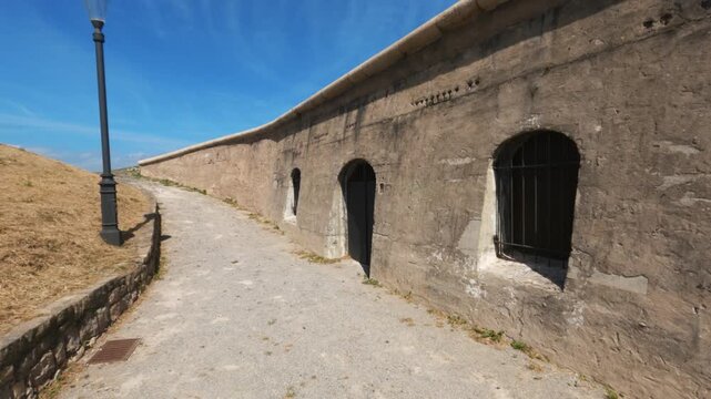 Walking path alongside ancient stone fortress wall with arched doorways at Santa Catalina battery in Gijon.