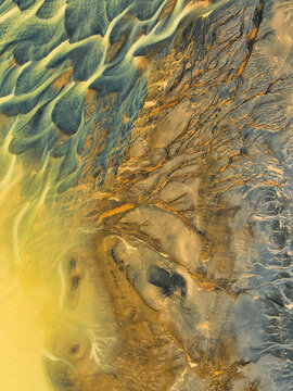 Aerial view of the intricate patterns and vibrant colors of a braided glacial river delta with sediment and volcanic soil in Hella, Rangarthing ytra, Iceland.