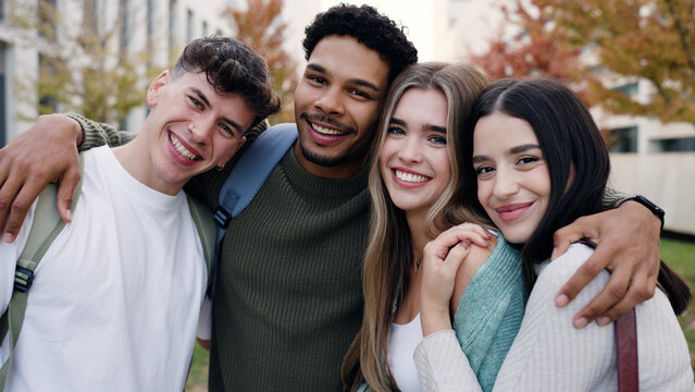 Group of happy young students smiling and embracing on a university campus, celebrating friendship and education outdoors
