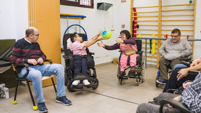 Group of people with disabilities engaged in a rehabilitation session, passing a ball during physical therapy