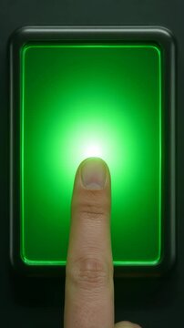 Finger pressing a glowing green button on a dark panel. Activating a futuristic interface.