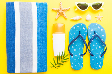 Naklejka premium Summer holiday concept. Top view of beach towel, flip flop and sunscreen cream on table Top view with copy space for text