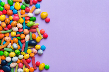 Fototapeta premium Mixed collection of colorful candy, on colored background. Flat lay, top view. frame of colorful chocolate coated candy