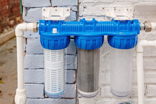 Three stage water filter system on a brick wall, purifying household water for safe drinking and home use