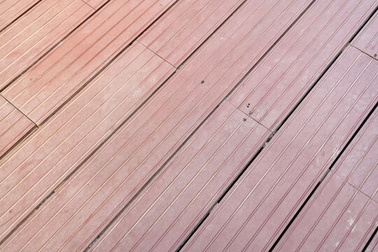 Reddish-brown composite decking boards with linear grooved texture background.