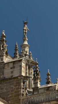Vertical architectural detail of ornate pinnacles and rooftop sculpture on Astorga Cathedral in Le&oacute;n, Spain. Gothic stone craftsmanship against a deep blue sky.
