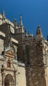 Vertical architectural view of Gothic facade details on Astorga Cathedral in Le&oacute;n, Spain. Historic stone ornamentation, pinnacles and decorative religious architecture under a clear blue sky.
