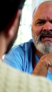 Indian male doctor consulting male patient during routine medical discussion as experienced physician advises young man inside modern Indian clinic OPD healthcare consultation
