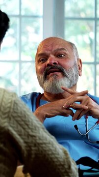 Indian male doctor consulting male patient during routine medical discussion as experienced physician advises young man inside modern Indian clinic OPD healthcare consultation