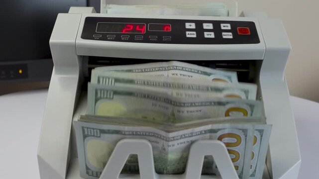 Electronic Money Counting Machine with Red Digital Display Processing a Stack of US 100 Dollar Bills