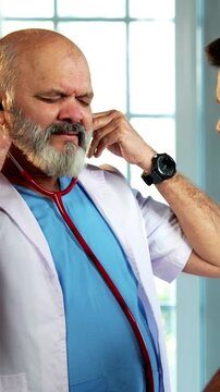 Indian male doctor treating patient during routine health checkup as experienced physician examines young man with stethoscope in modern Indian clinic OPD healthcare consultation visit