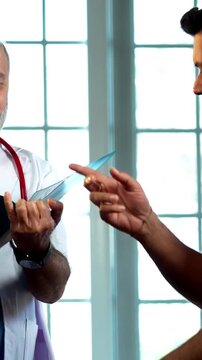 Indian male doctor consulting male patient with medical report as experienced physician advises young man inside modern Indian clinic OPD healthcare consultation